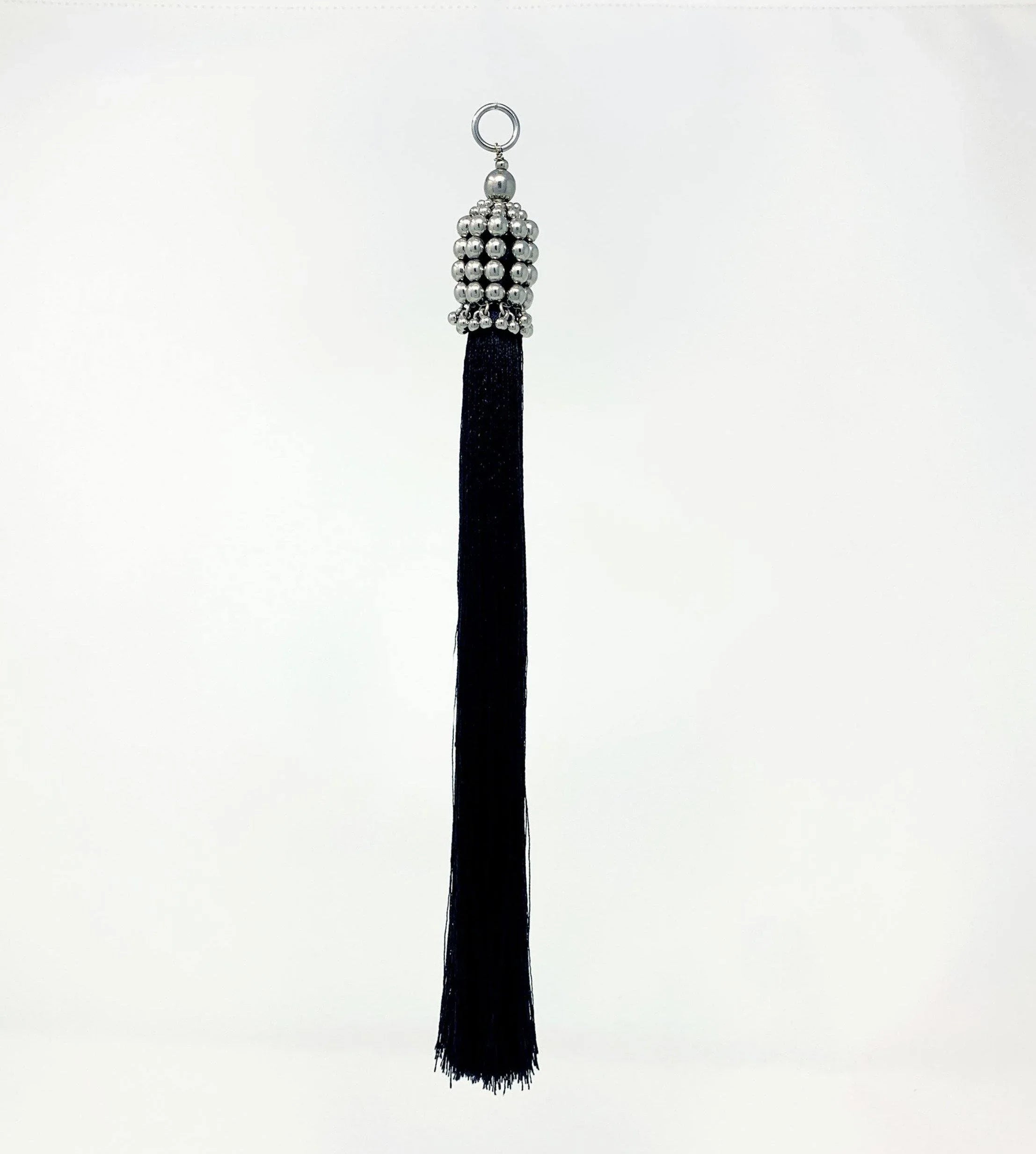 beaded modular tassel ith silver cap and black threads in white background by object and dawn