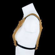 Profile view of a gold beaded top on a white mannequin against a black background