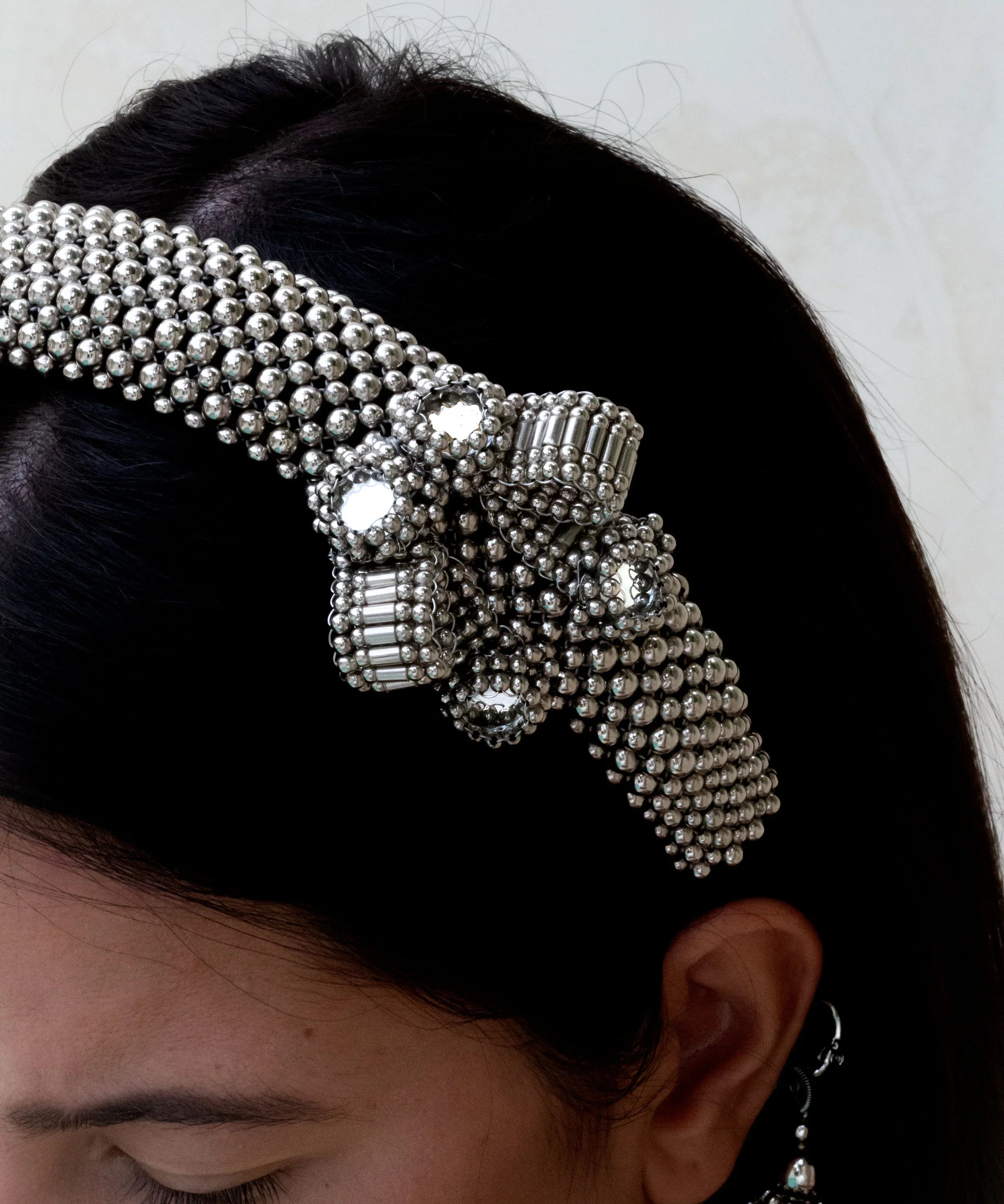 Object & Dawn Amaya Bow Headband silver detail view worn by woman in neutral bankground