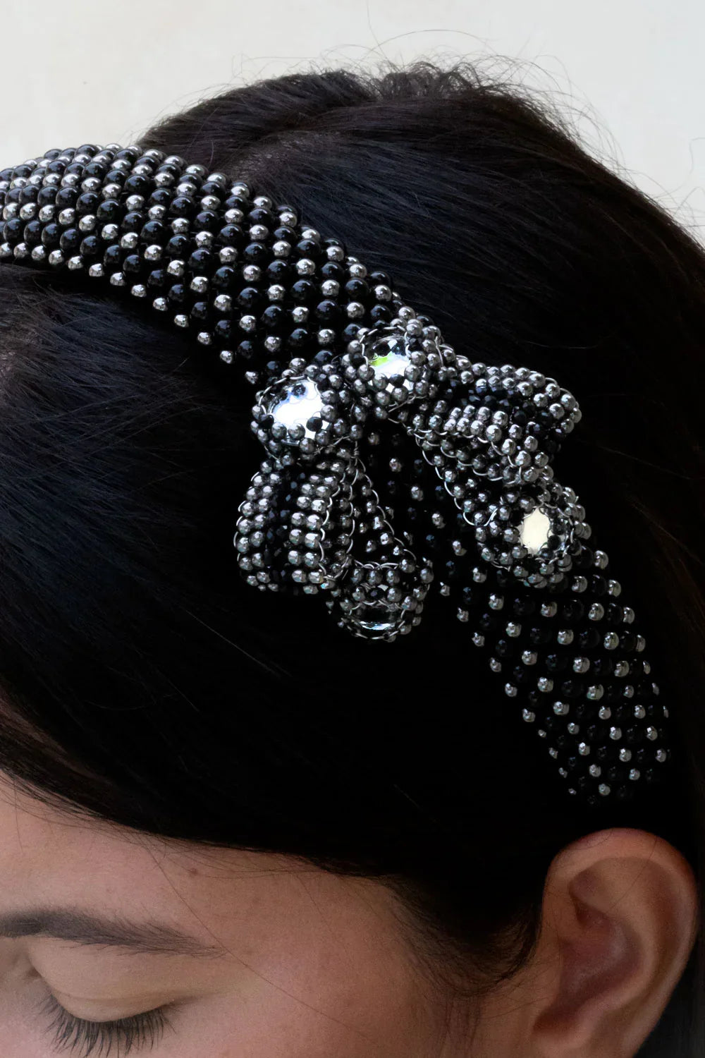 close up of woman with handcrafted Silver beaded  with black crystals amaya headband  by Object & Dawn worn by a person with a neutral background 
