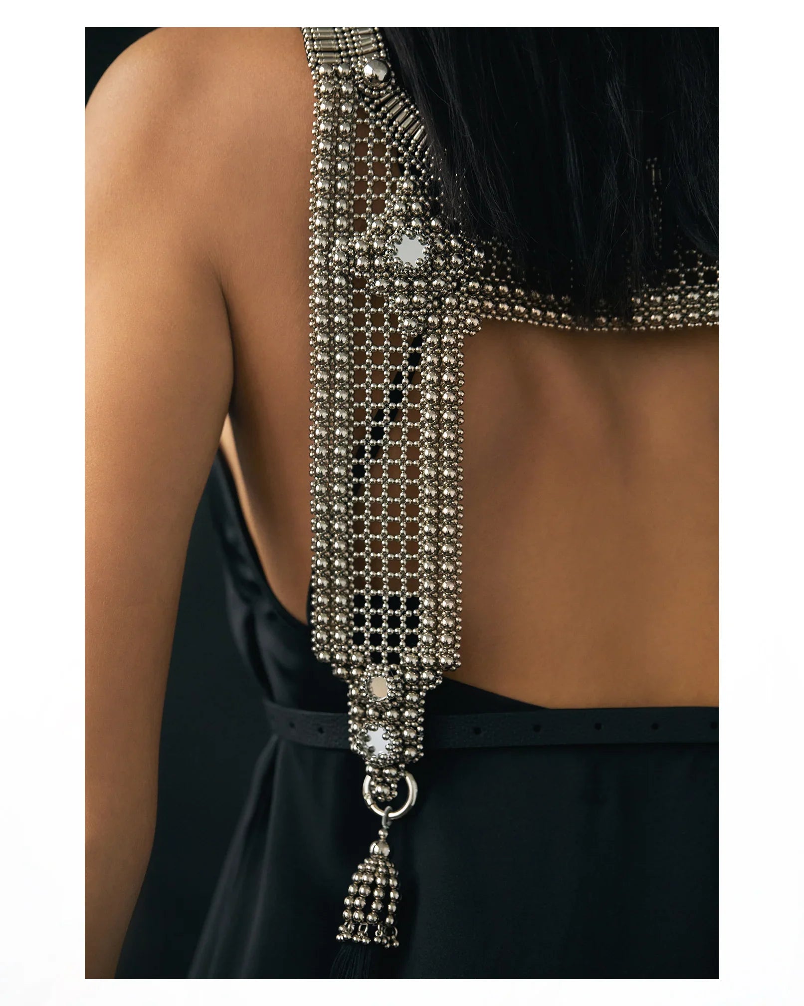 Woman wearing a black dress with silver beaded top and matching choker necklaces on white background close up 