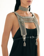 torso of woman wearing silver beaded top and matching choker over black dress on a white background