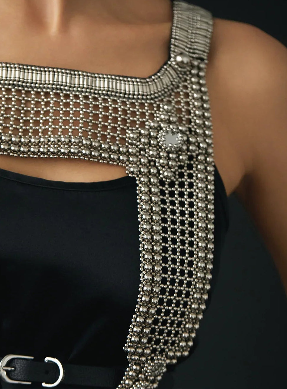 Closeup torso view of silver beaded top over black dress. 
