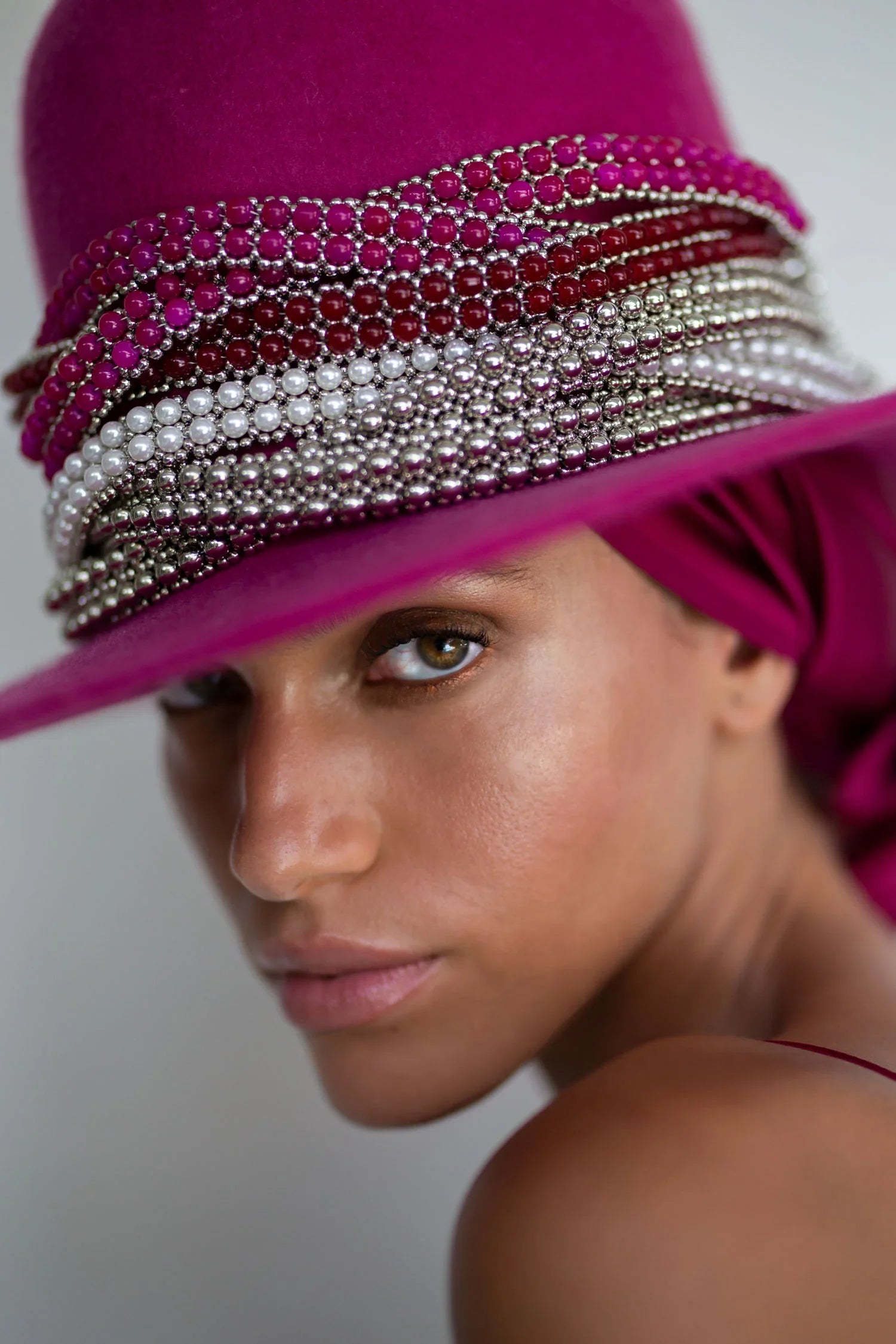 close up of mix hat band accecories pink red pearl silver on pink hat worn view in grey background by object and dawn