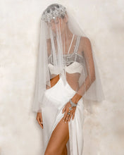 Woman wearing a white silk skirt with a long veil, Khutulun Top and pearl crown by Object & Dawn  against a creme background
