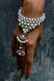 Closeup of Pearl bracelet and ring by Object & Dawn on a hand against a dark background