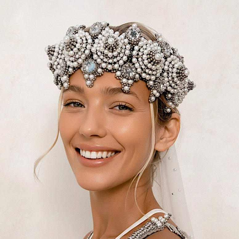 Woman wearing a decorative headpiece with pearls and crystals on a plain background