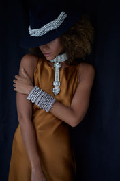 woman in brown dress with black hat wear beaded modular choker in pearl from Object and Dawn front view