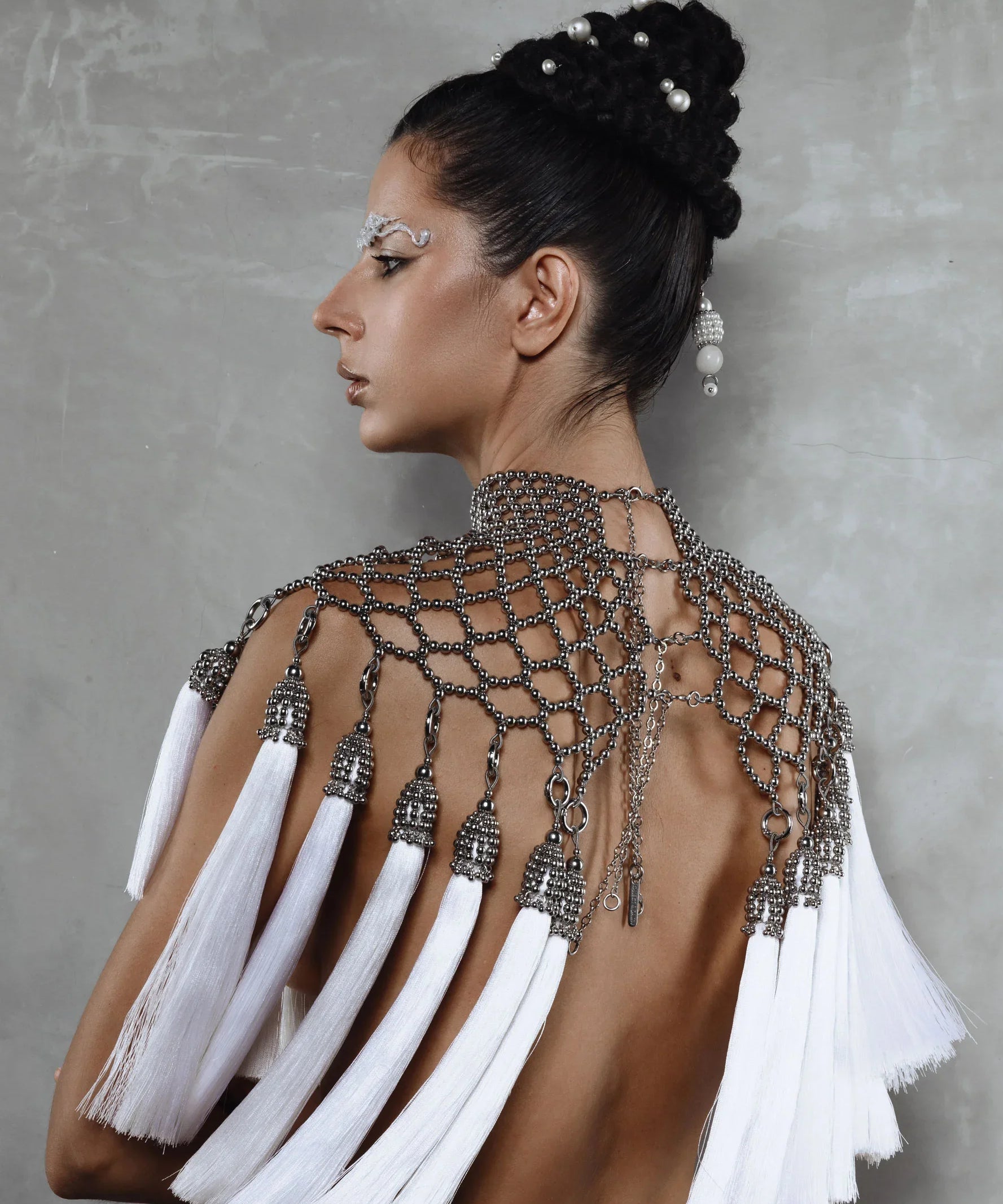 Beaded handcrafted polyester tassel by silver coated metal beads on Freja modular cape in silver on grey background