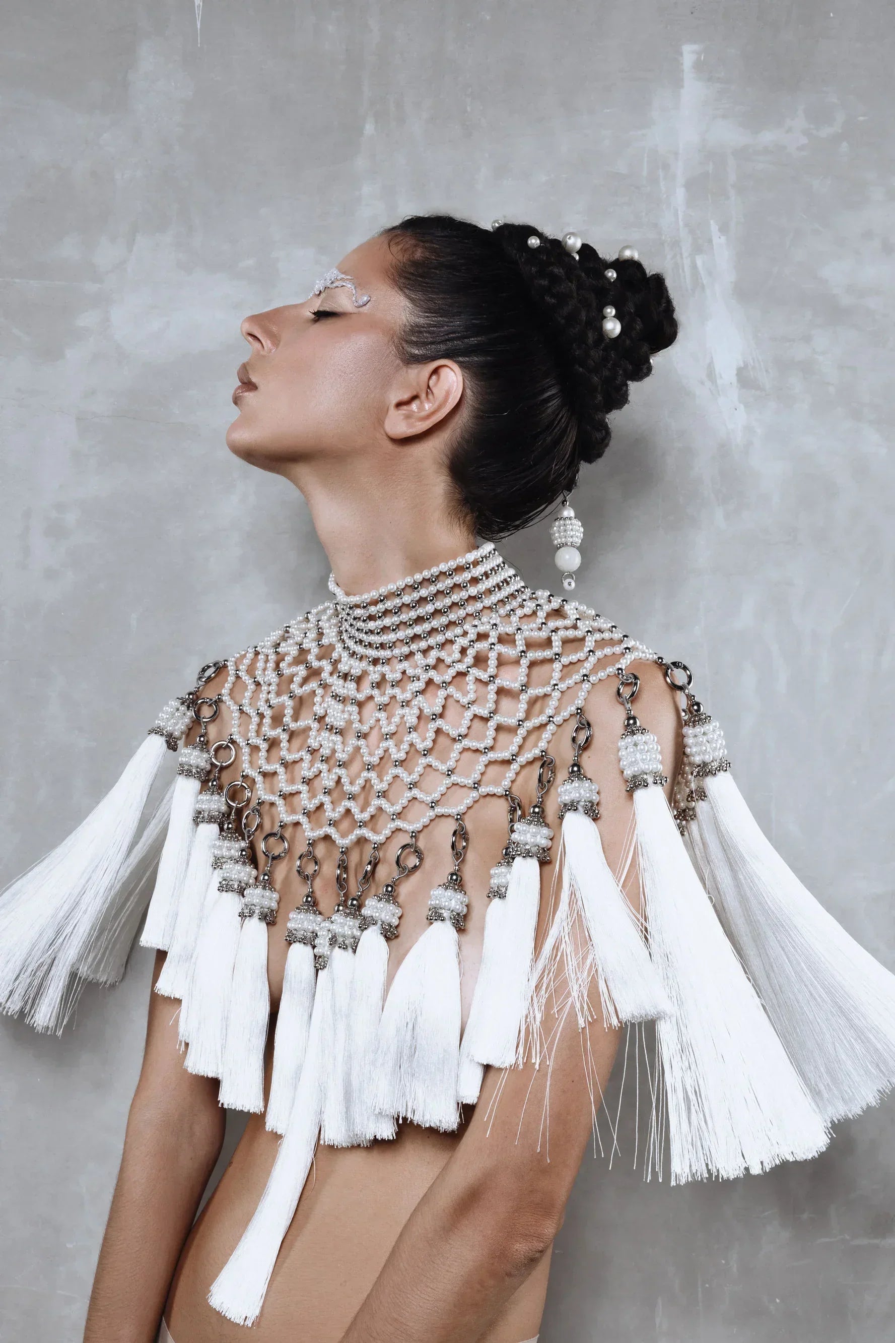 Beaded handcrafted polyester tassel by silver coated metal beads with systethic japanese pearl on Freja Modular Cape on grey background