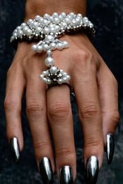 Hand wearing Mata Hari pearl bracelet and a ring by Object & Dawn on a dark background