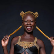Woman wearing a beaded gold headband with cat like earpieces atop against a dark background