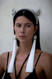 Woman wears Jas Headband pearl with 11" tassels gold-black by Object & Dawn in neutral backgorund
