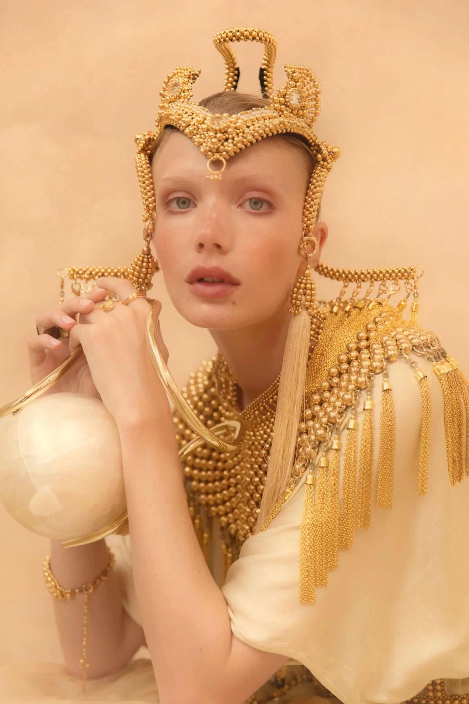 Jolina with handcrafted modular jas headpiece system with 22k gold wash on polymer beads with removable tassels on gold background