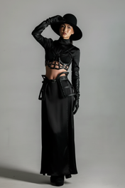 Woman wearing a black outfit with Jas Leather Cage Skirt & Cage Top by Object & Dawn and gloves against a gray background