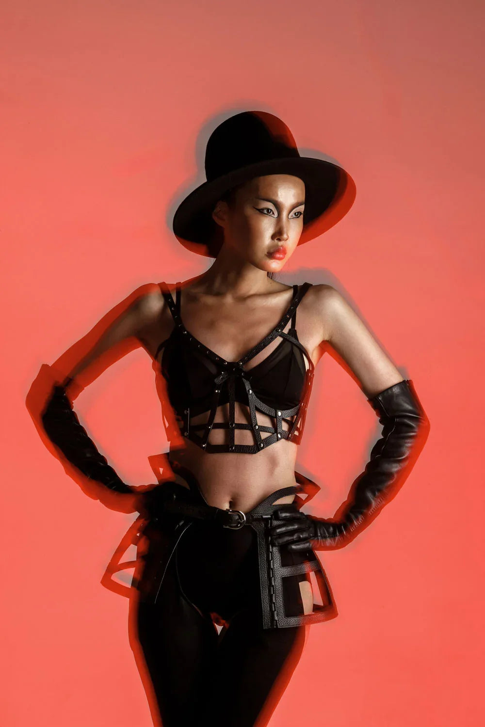 woman with premium leather studded cage top black on red background front view half body