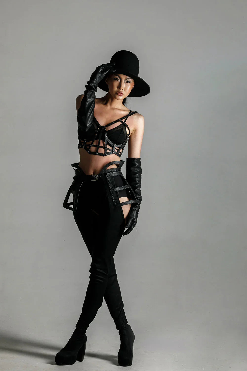 woman with premium leather studded cage top black on grey background front view