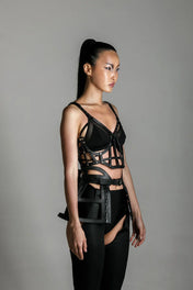 woman with premium leather studded cage top black on grey background
