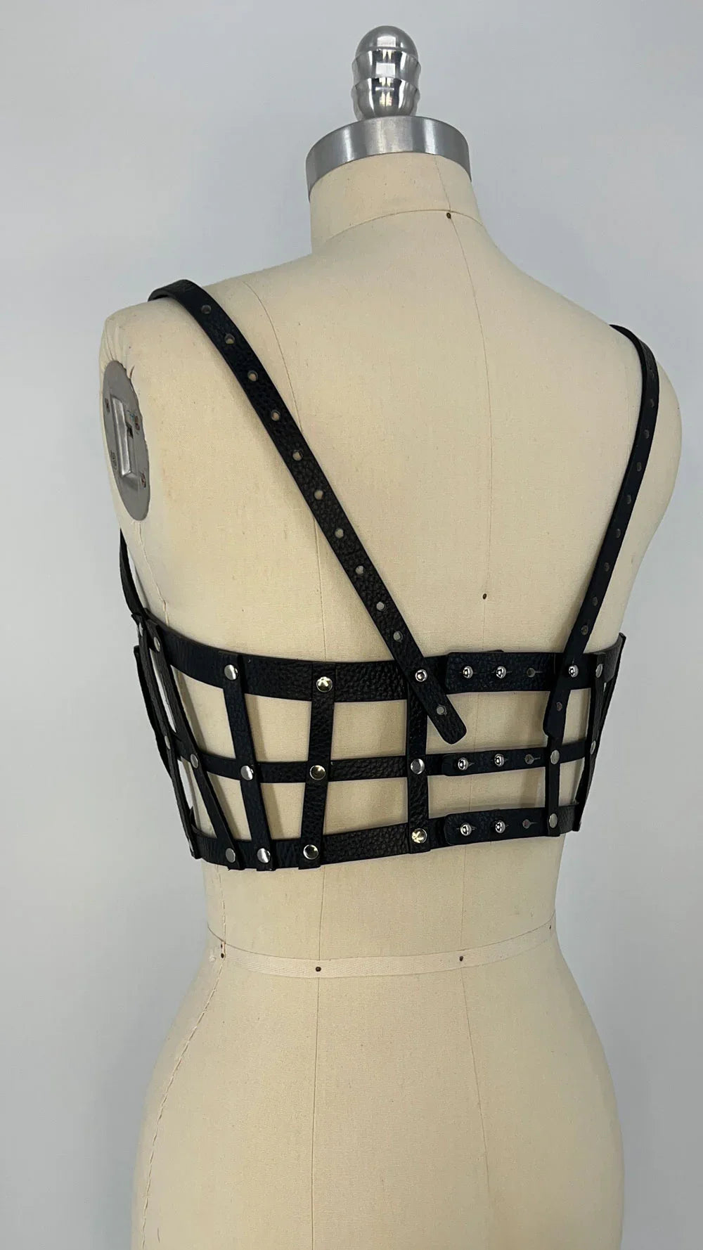 ghost image premium leather studded cage top black on mannequinwith  grey background back diagonal