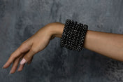 hand of person with handcrafted modular cuff in jet black from hundreds of beads by object and dawn