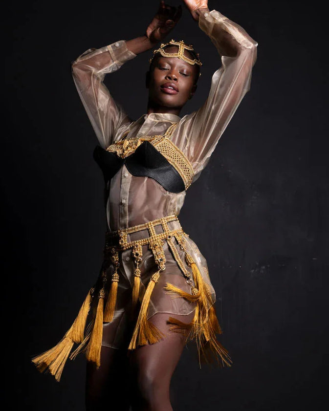 Dancer wearing a gold beaded Amaya belt with gold accents against a dark background