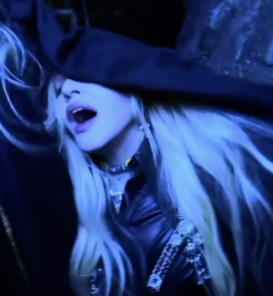 Madonna wearing Object & Dawn harness in video. Blue toned lighting.