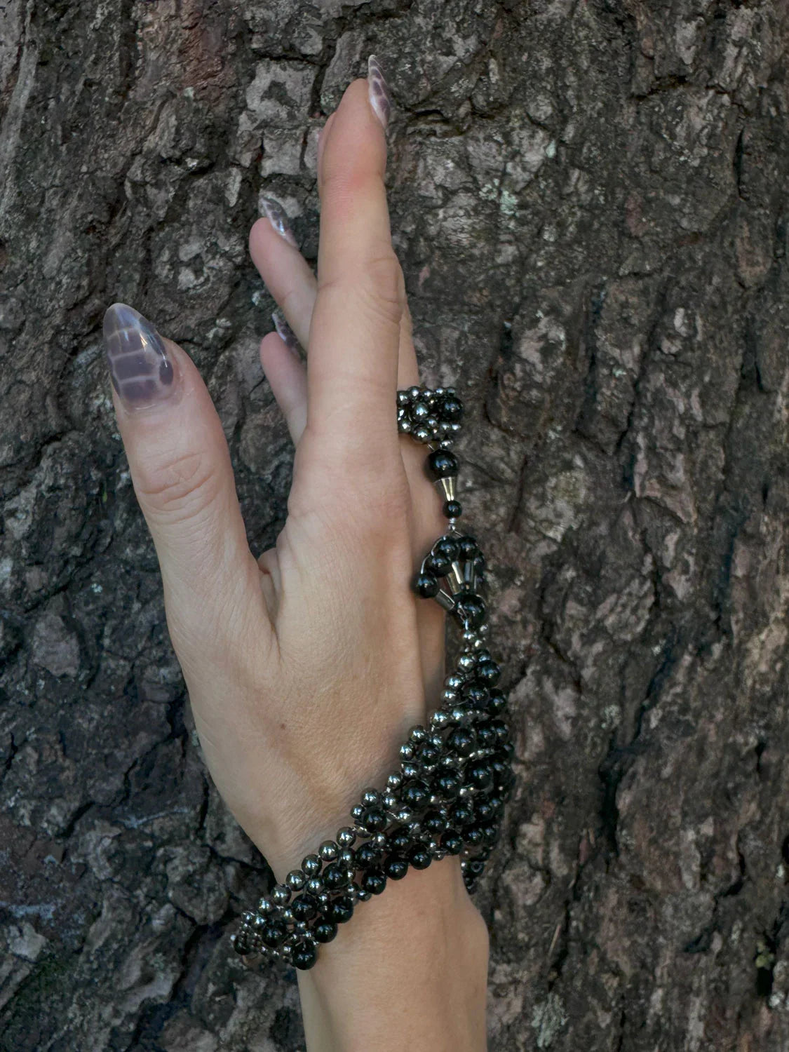 luxury beaded hand jewelry polymer metal beads and crystal black on hand with wood background by object and dawn