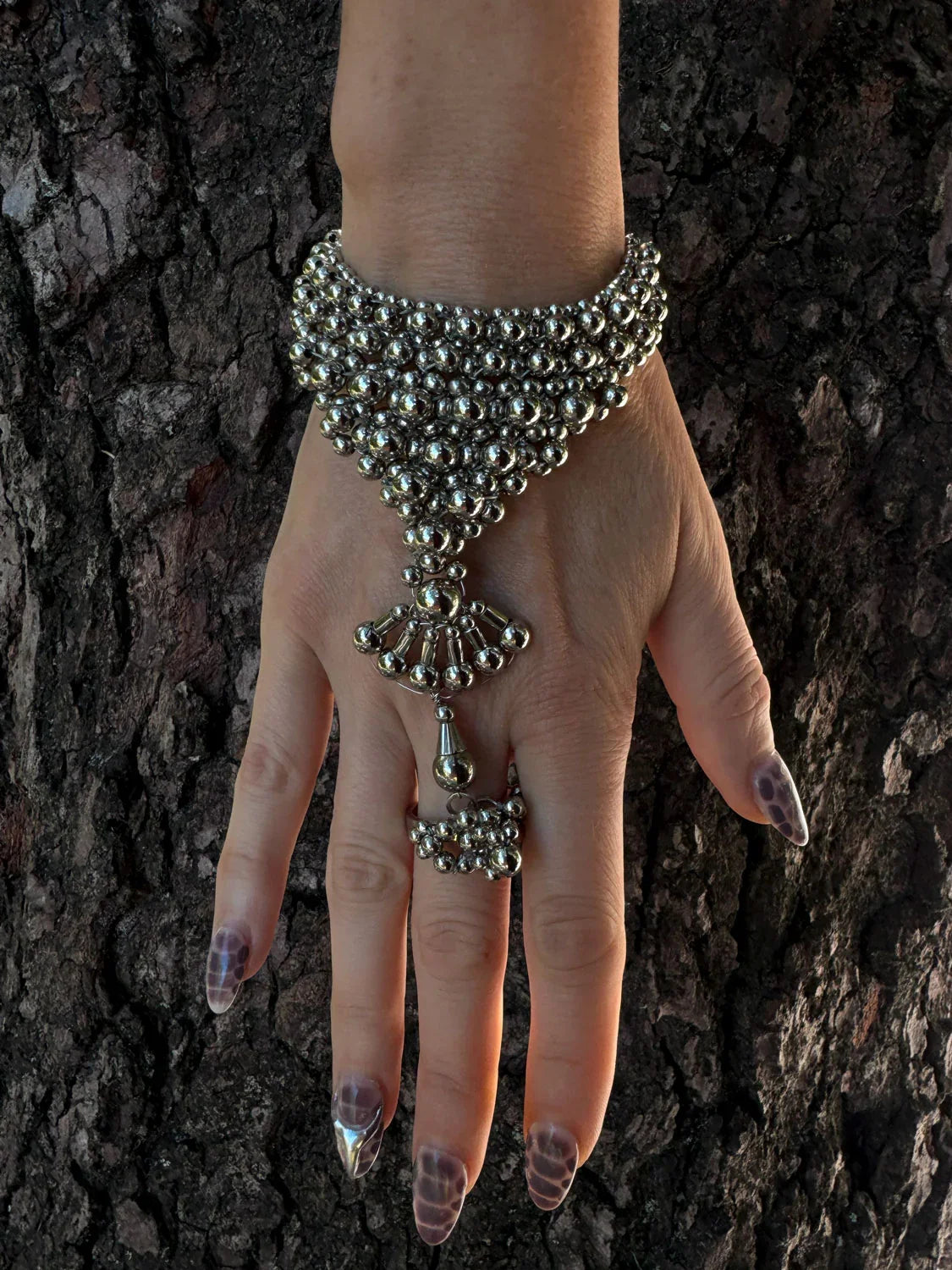 luxury beaded hand jewelry polymer metal beads silver on hand with wood background by object and dawn