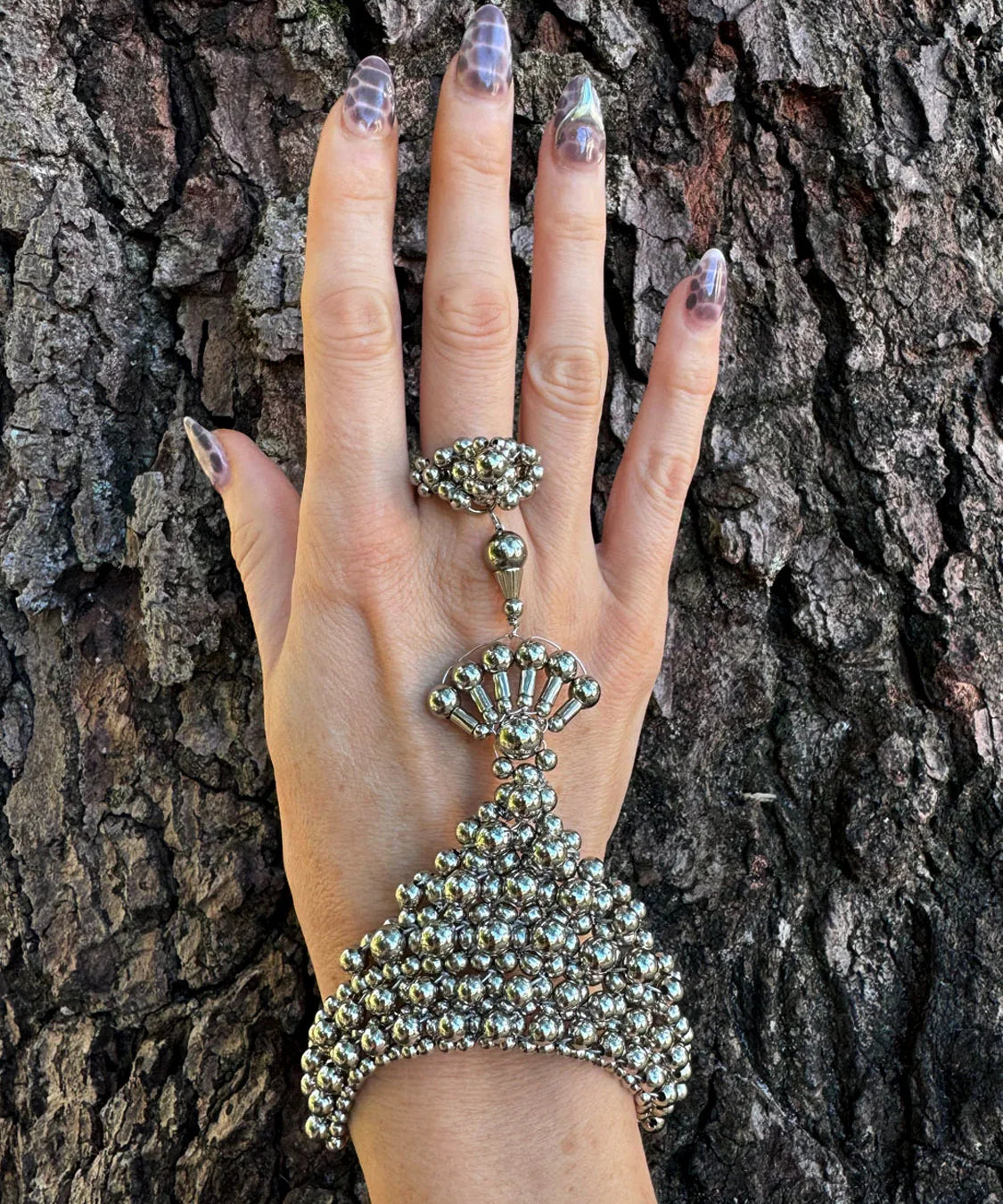 handcrafted mata hari ring silver on hand in wood background by object and dawn front view