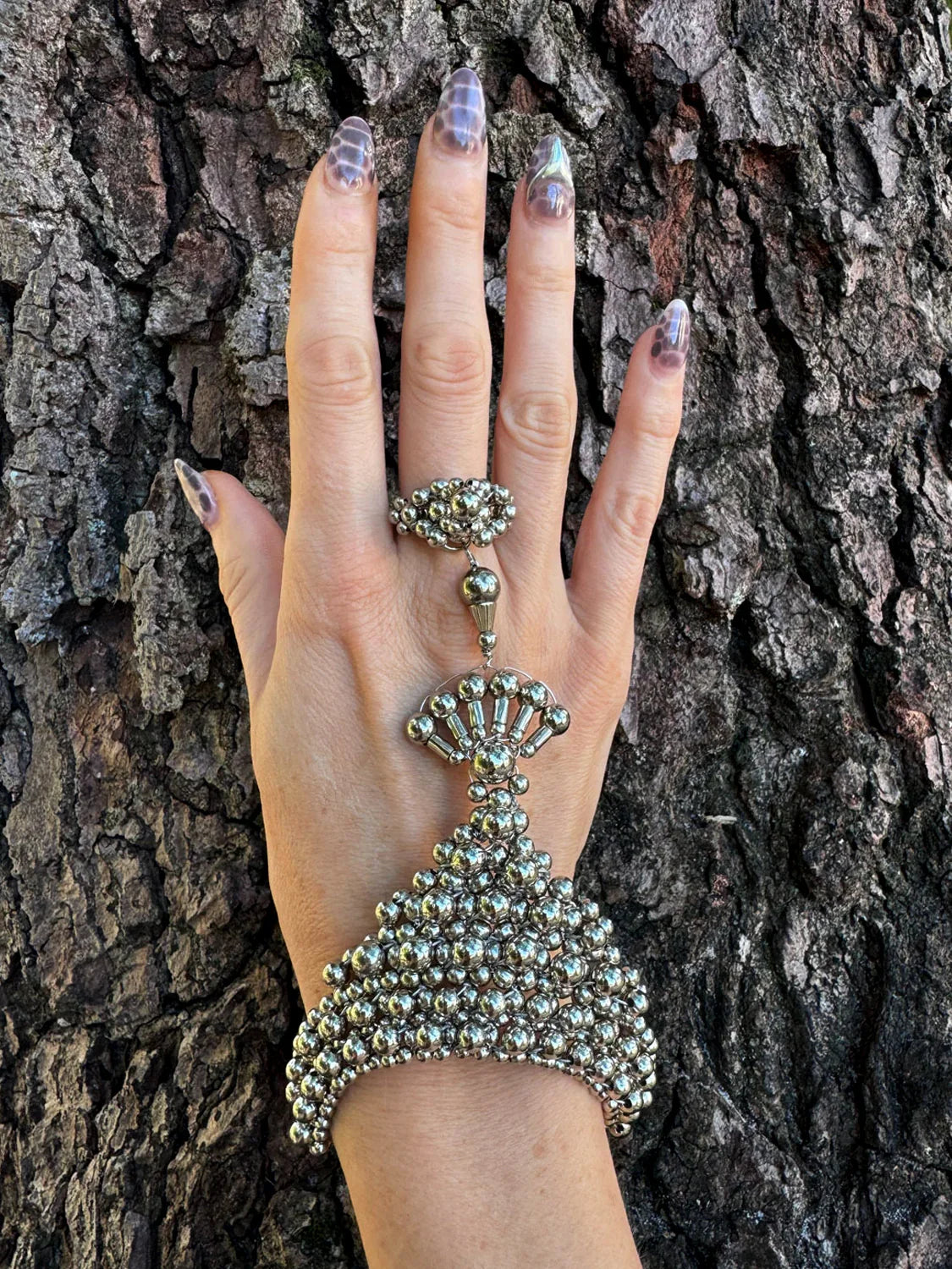 handcrafted mata hari ring silver on hand in wood background by object and dawn front view