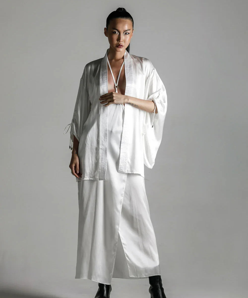 short white silk kimono with white harness skirt worn on woman by object and dawn at neutral background front view
