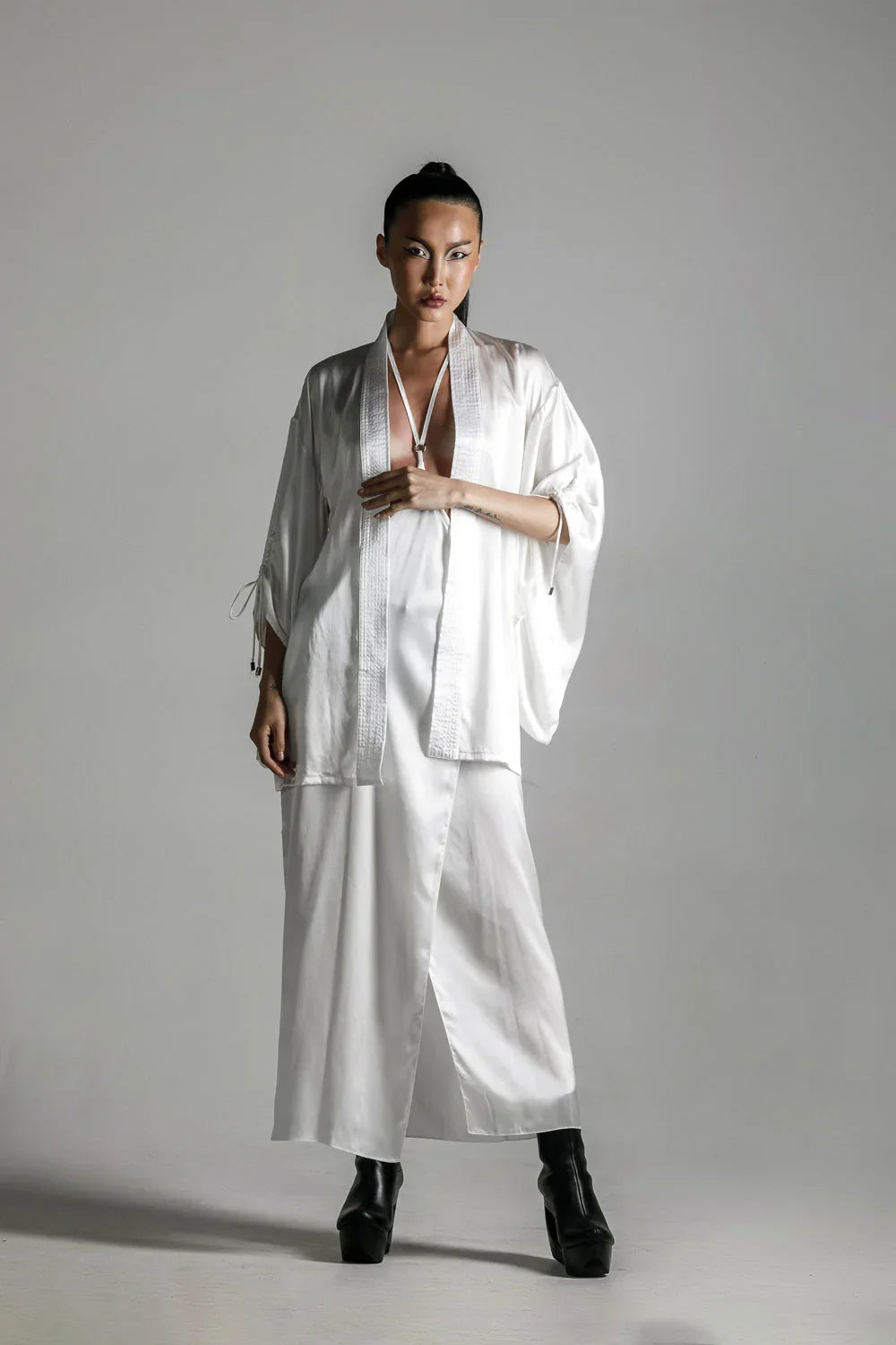 short white silk kimono with white harness skirt worn on woman by object and dawn at neutral background front view