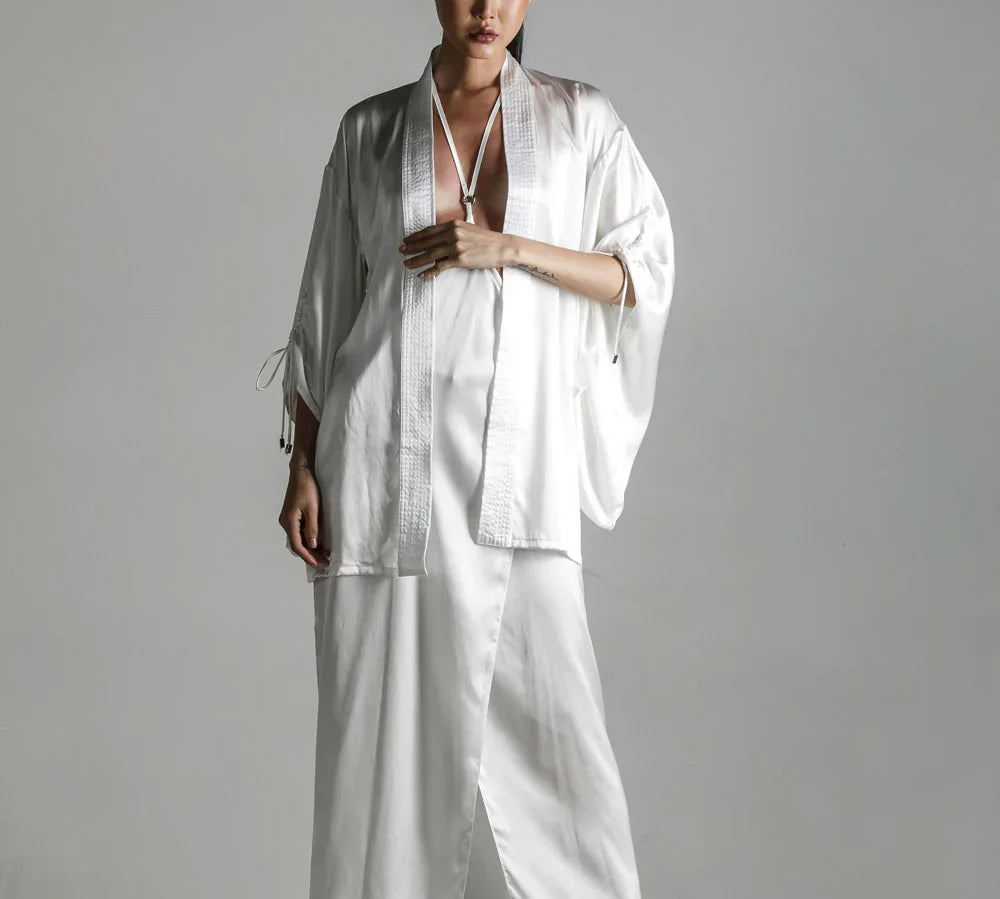 short white silk kimono with white harness skirt worn on woman by object and dawn at neutral background front view