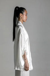 short white silk kimono worn on woman by object and dawn at neutral background side view