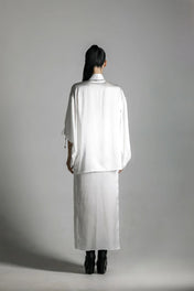 short white silk kimono with white harness skirt worn on woman by object and dawn at neutral background back view