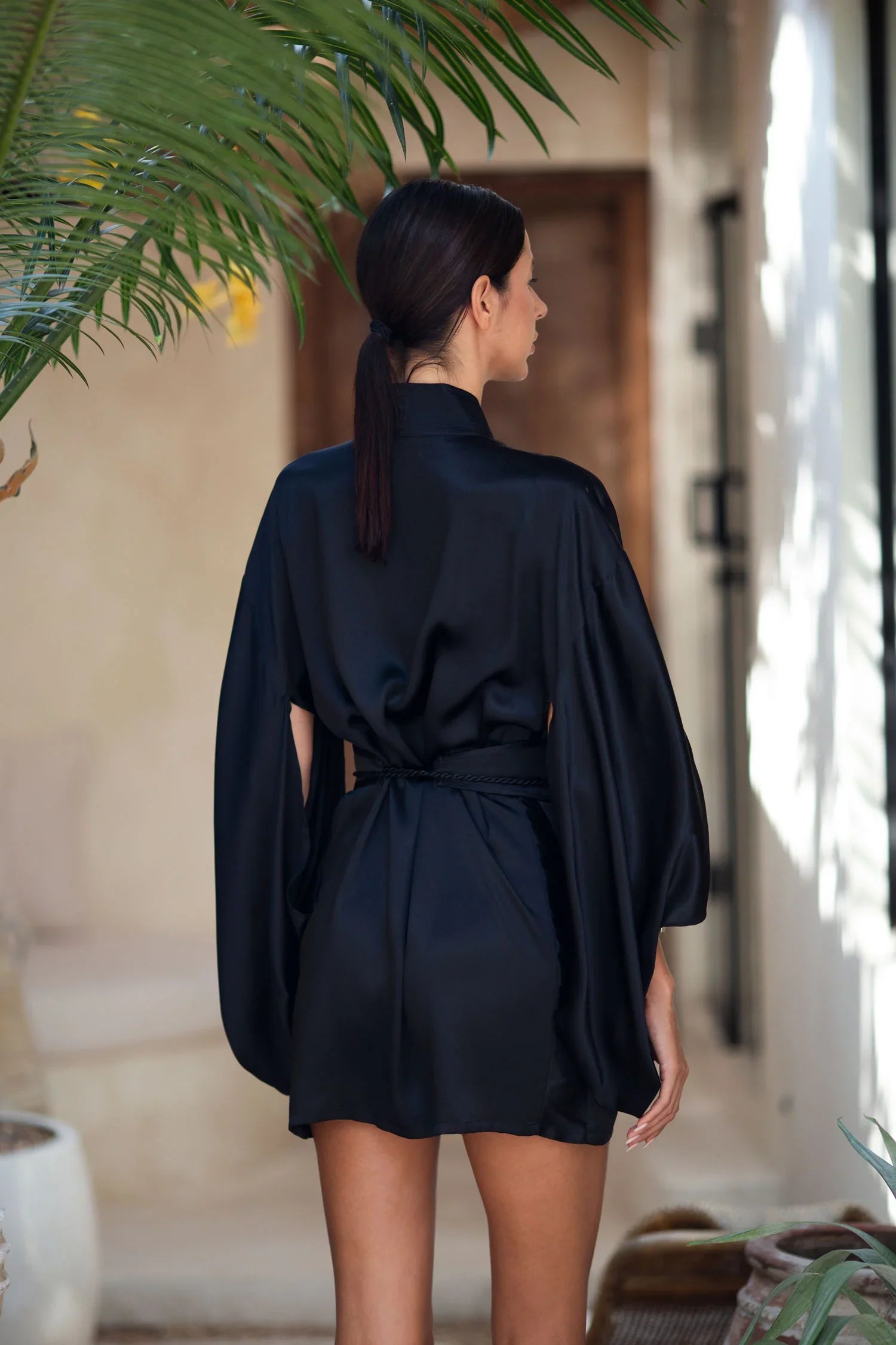 short black silk kimono with obi belt worn view from back by object and dawn at neutral background
