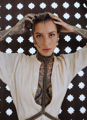 woman with tattoes in beidge outfit wear t shape choker harness antique gold by object and dawn in stars background