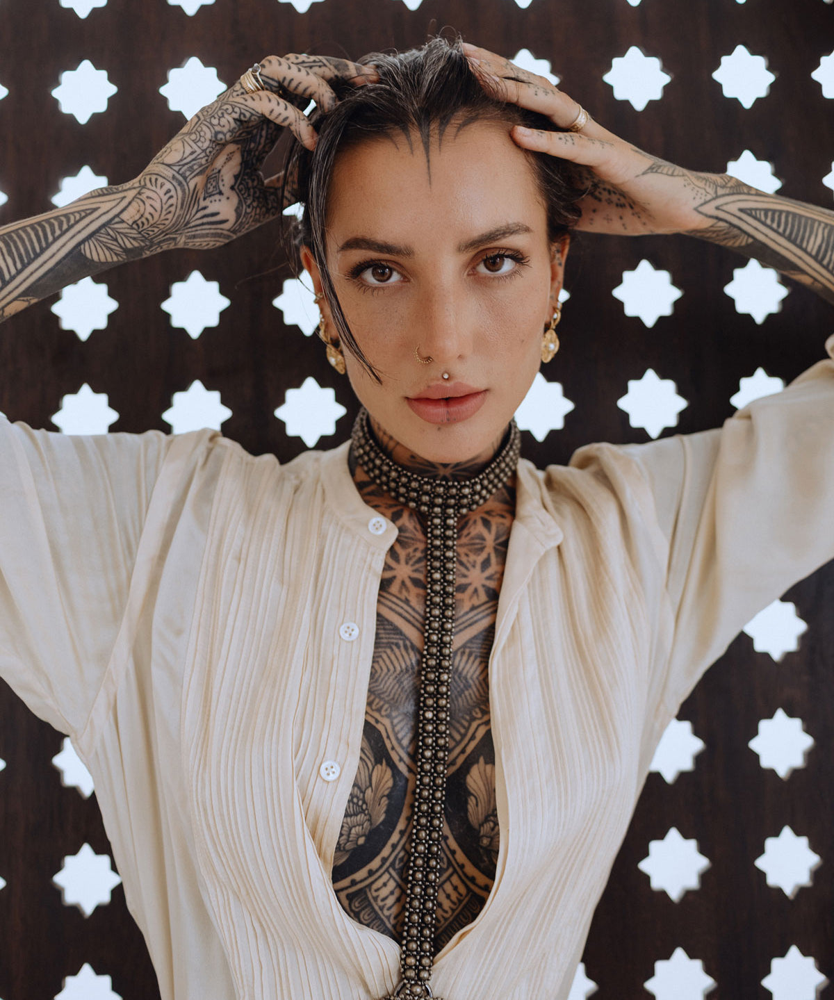 woman with tattoes in beidge outfit wear t shape choker harness antique gold by object and dawn in stars background