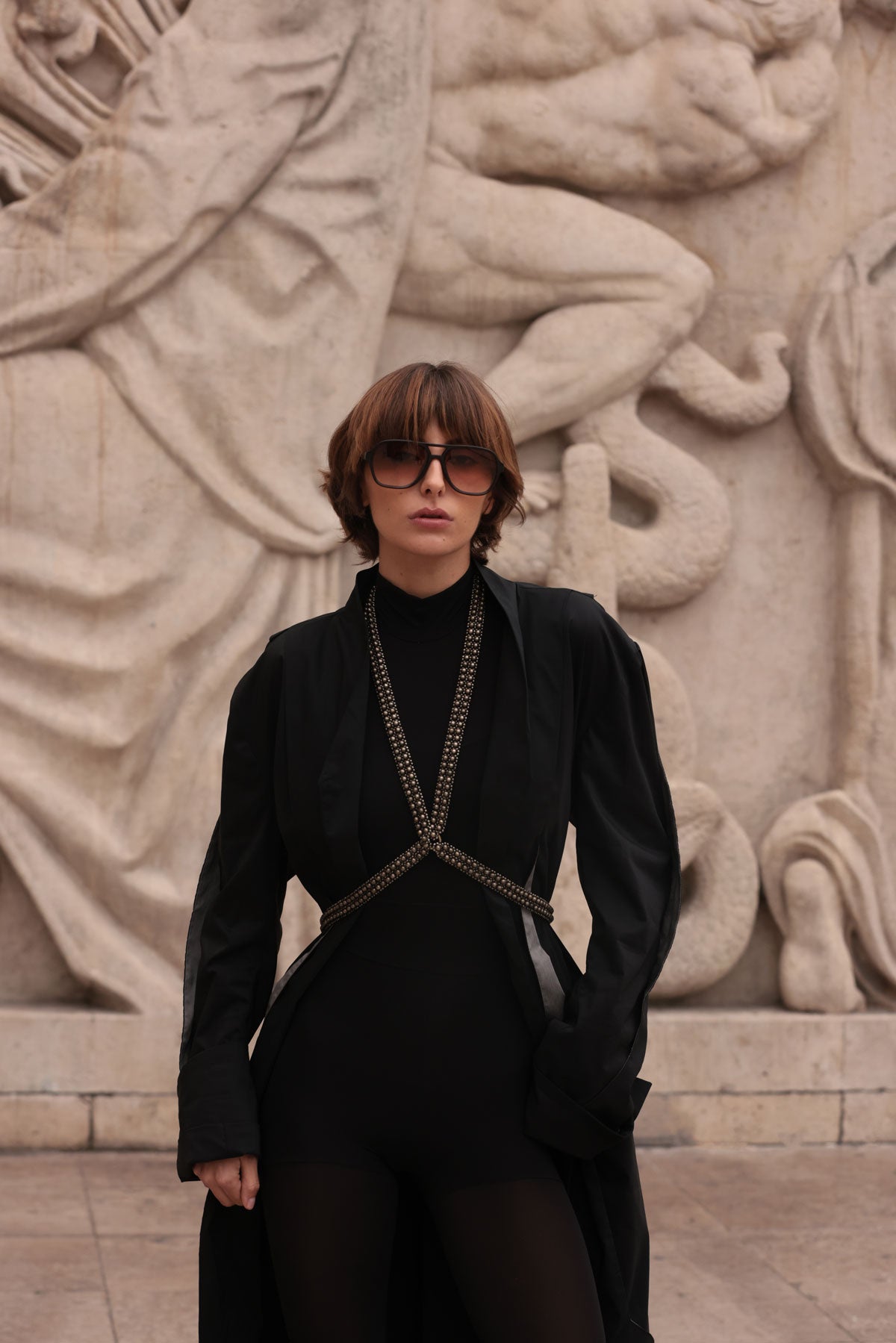 Woman wearing a black outfit with V-Neck Beaded Harness in front of a stone sculpture by Object & Dawn