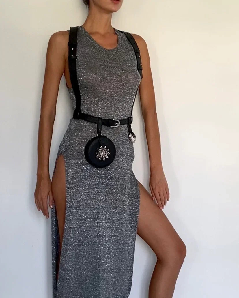 woman in grey dress wears Zheng leather harness with beaded coin back by object & dawn in white background