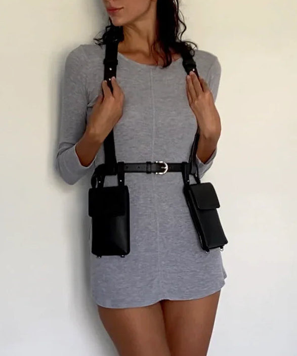 Woman wearing a gray dress with black harness against a white background