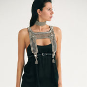 Brunette woman wearing a black dress with beaded silver top and choker.